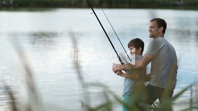 Excited father and son pulling fish out from lake