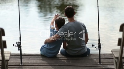 Affectionate father embracing son as they fish