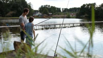 Positive dad and son with rod angling at pond