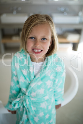 Smiling girl standing near bathtub in bathroom