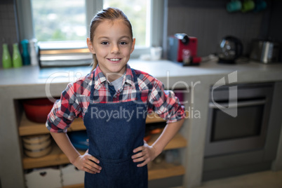 Smiling girl posing wearing an apron in the kitchen