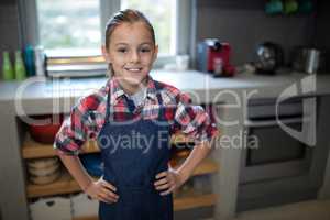 Smiling girl posing wearing an apron in the kitchen