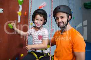 Trainer assisting boy in rock climbing at fitness studio