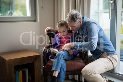 Father and daughter reading a book at home