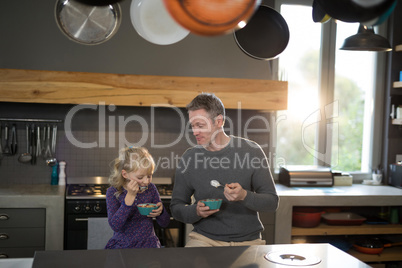 Little girl and father posing while eating fruits from a bowl