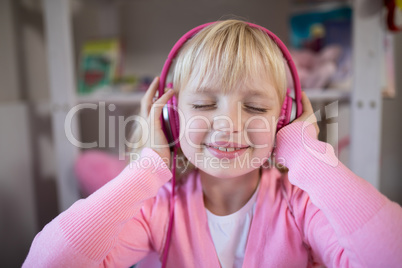 Cute girl listening to pink headphones