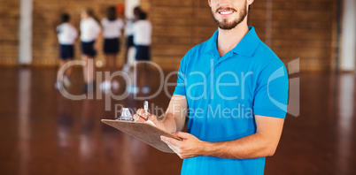 Portrait of sports teacher writing on clipboard