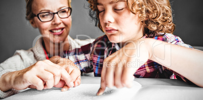 Teacher with boy using braille to read