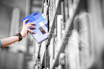 Students hand with smartwatch picking book from bookshelf