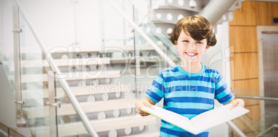 Composite image of portrait of smiling boy holding book