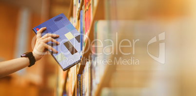 Students hand with smartwatch picking book from bookshelf