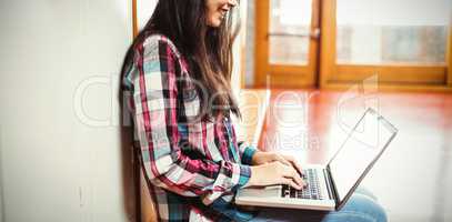 Smiling student using laptop sitting at university