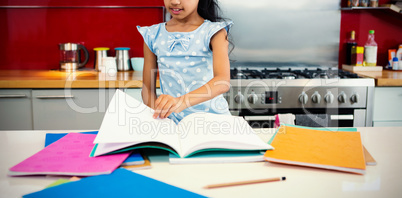 Girl flipping pages of book in kitchen