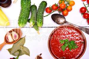 Fresh gazpacho soup in a brown ceramic dish with a spoon