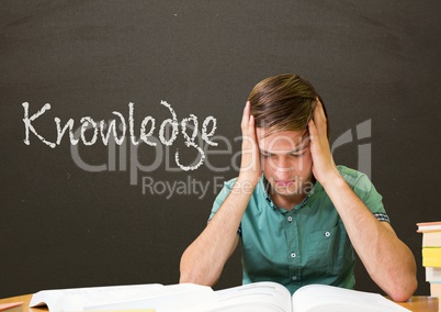 Worried student boy at table against grey blackboard with knowledge text