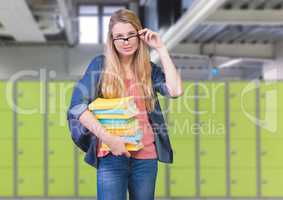 female student holding books in front of lockers