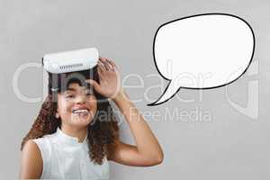 Happy young woman with speech bubble holding a VR headset against grey background