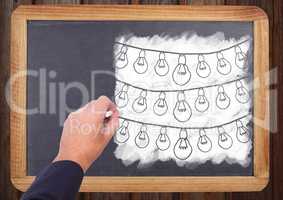 Hand drawing light bulbs on blackboard