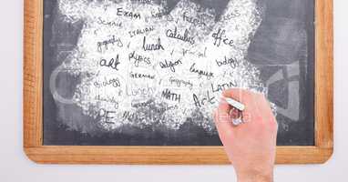 Hand writing school subjects on blackboard