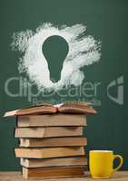 Books on the table against green blackboard with bulb graphic