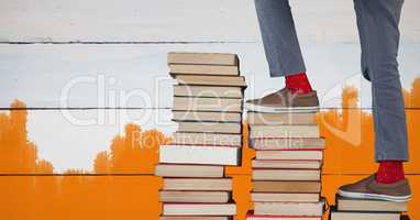 Feet walking up book steps and orange painted background