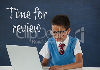 Student boy at table using a computer against blue blackboard with time for review text