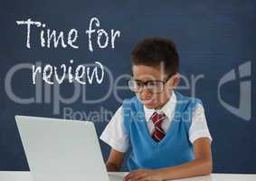 Student boy at table using a computer against blue blackboard with time for review text
