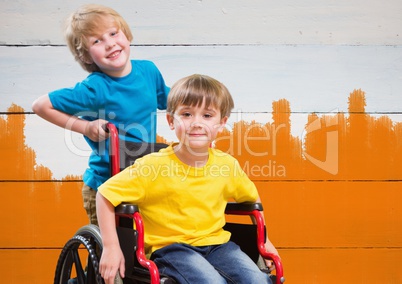 Disabled boy in wheelchair with friend with bright orange painted  background