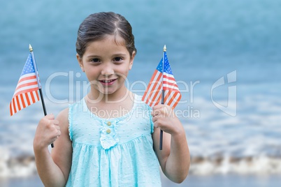 Girl holding USA flags in the beach