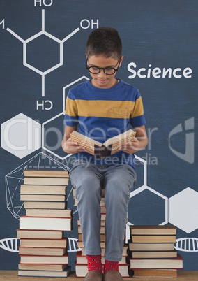 Student boy on a table reading against blue blackboard with science text and graphics