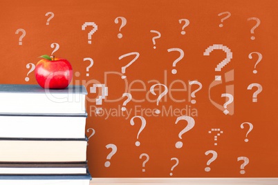 Books on the table against orange blackboard with question marks