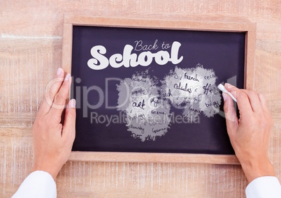 Hand writing school subjects and back to school text on blackboard