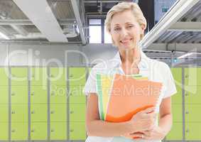 mature female student holding book in front of lockers