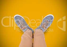 Grey shoes on feet with yellow background