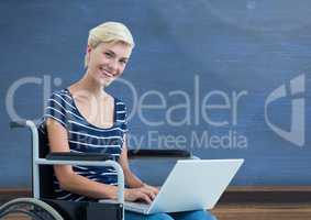 Disabled woman in wheelchair on laptop in front of blackboard