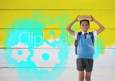 Schoolboy holding books on head with painted yellow background and settings cogs gears