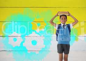 Schoolboy holding books on head with painted yellow background and settings cogs gears