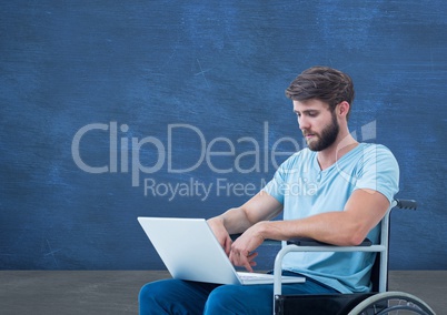 Disabled man in wheelchair on laptop in front of blackboard