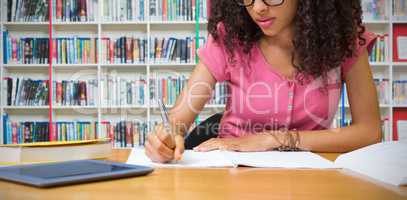 Composite image of student sitting in library writing