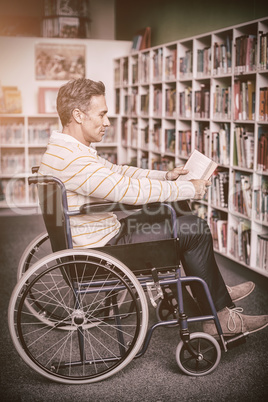 Attentive disabled school teacher reading book in library