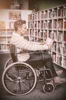 Attentive disabled school teacher reading book in library