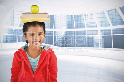 Composite image of smiling girl balancing books and apple on head