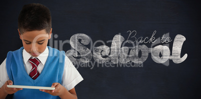 Composite image of schoolboy using digital tablet