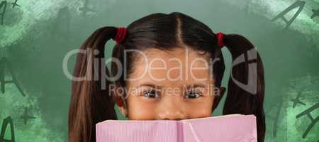 Composite image of schoolgirl covering mouth with book