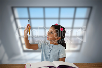 Composite image of girl looking at pencil while sitting at desk