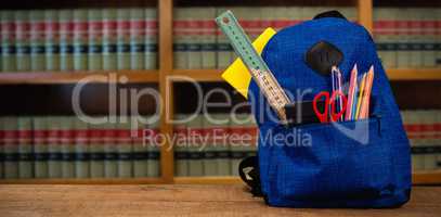 Composite image of schoolbag on wooden table