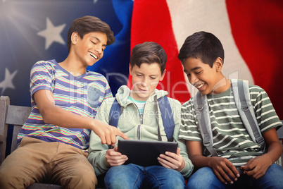 Composite image of boy with friends using digital tablet on bench