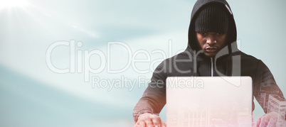 Composite image of serious male hacker with laptop