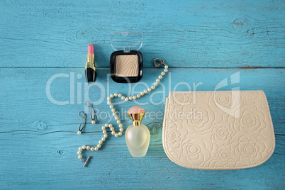 Cosmetics, perfumes, jewelry made of pearls and handbag on an ol
