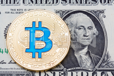 Golden blue bitcoin coin on us dollars close up.